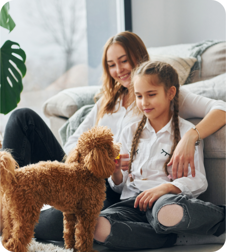 Girl sitting with her sister and playing with her dog.